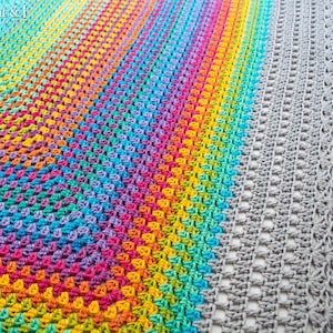 May include: A rainbow crochet blanket with a gray crochet border. The blanket is made with a variety of colors, including red, orange, yellow, green, blue, indigo, and violet. The blanket is crocheted in a circular pattern, with the colors gradually blending into each other. The border is crocheted in a simple stitch, with a scalloped edge.