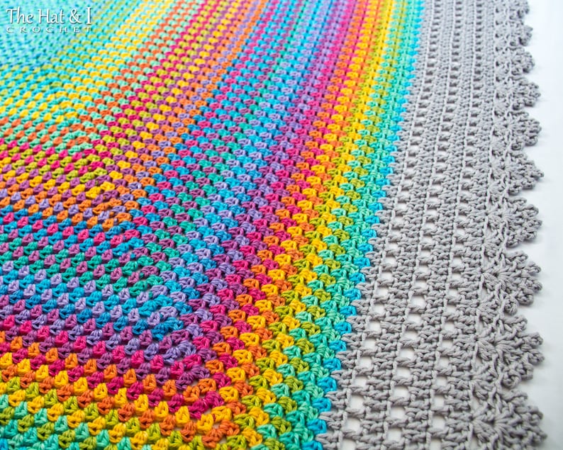May include: A rainbow crochet blanket with a gray crochet border. The blanket is made with a variety of colors, including red, orange, yellow, green, blue, indigo, and violet. The blanket is crocheted in a circular pattern, with the colors gradually blending into each other. The border is crocheted in a simple stitch, with a scalloped edge.