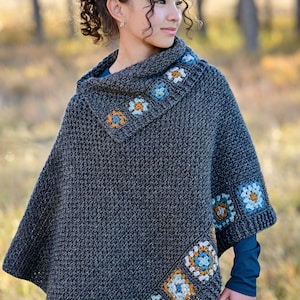 May include: A dark gray crochet poncho with a cowl neck and floral square accents in blue, orange, and white. The poncho has a textured stitch pattern and is worn by a person. The text "The Hat & I Crochet" is visible in the upper right corner.