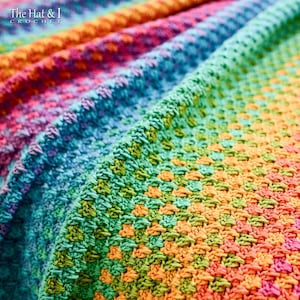 May include: A close-up of a colorful crochet blanket with a rainbow pattern. The blanket is made with a variety of different colored yarns, creating a vibrant and cheerful design.