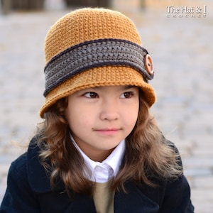 May include: A brown and tan crocheted newsboy hat with a brown button. The hat has a wide brim and a contrasting band.