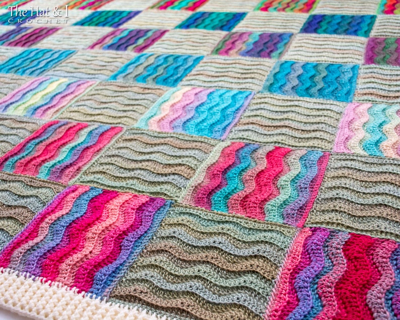 Pode incluir: Uma manta de croch&ecirc; colorida com um padr&atilde;o ondulado. A manta &eacute; composta por quadrados de diferentes cores, incluindo rosa, azul, verde e marrom. A manta &eacute; feita de croch&ecirc; com uma borda branca.