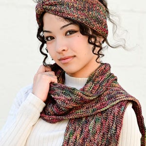 May include: A multi-colored knit headband and scarf set. The headband is wrapped around the head, and the scarf is draped around the neck. The set is made of a yarn with red, green, and yellow hues. The text "The Hat & I Crochet" is in the upper right corner.