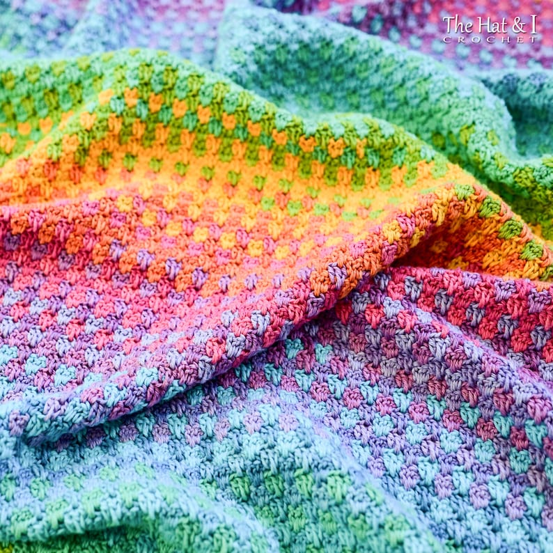 May include: A rainbow crochet blanket with a textured stitch pattern. The blanket is folded in half, showing the different colors of the yarn.