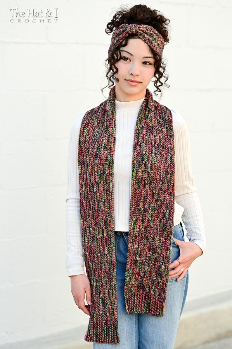 May include: A multi-colored knitted scarf and matching headband. The scarf is long and rectangular, with a textured pattern in shades of red, green, and black. The headband has a similar design. The Hat & I Crochet logo is in the top left corner.