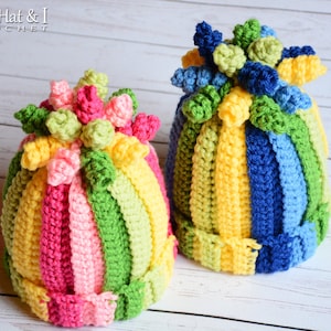 May include: Two colourful crocheted hats with a striped design and a pom-pom on top. The hats are made with bright colours like pink, yellow, green, and blue.