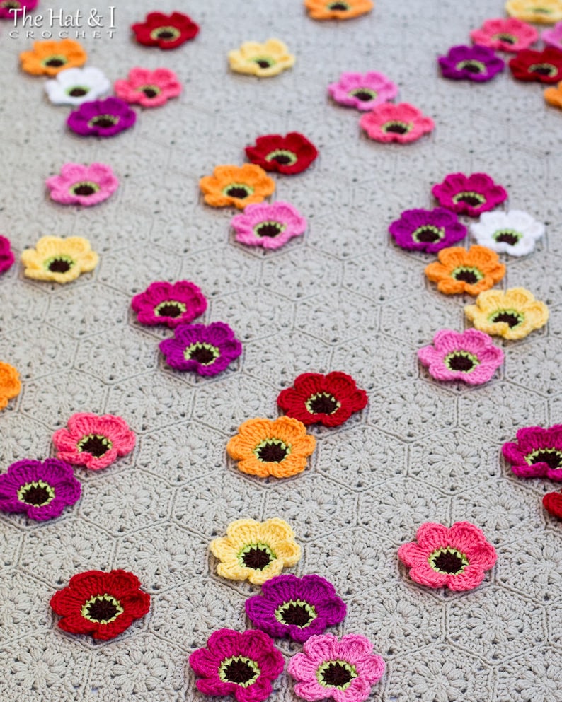 May include: A crocheted blanket with a gray background and colorful crocheted flowers in various colors, including pink, red, yellow, orange, and purple.