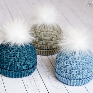 May include: Three crocheted hats with white pom-poms. The hats are in shades of blue and grey.