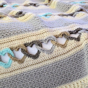 May include: A crocheted blanket with a heart pattern in shades of gray, beige, and teal.