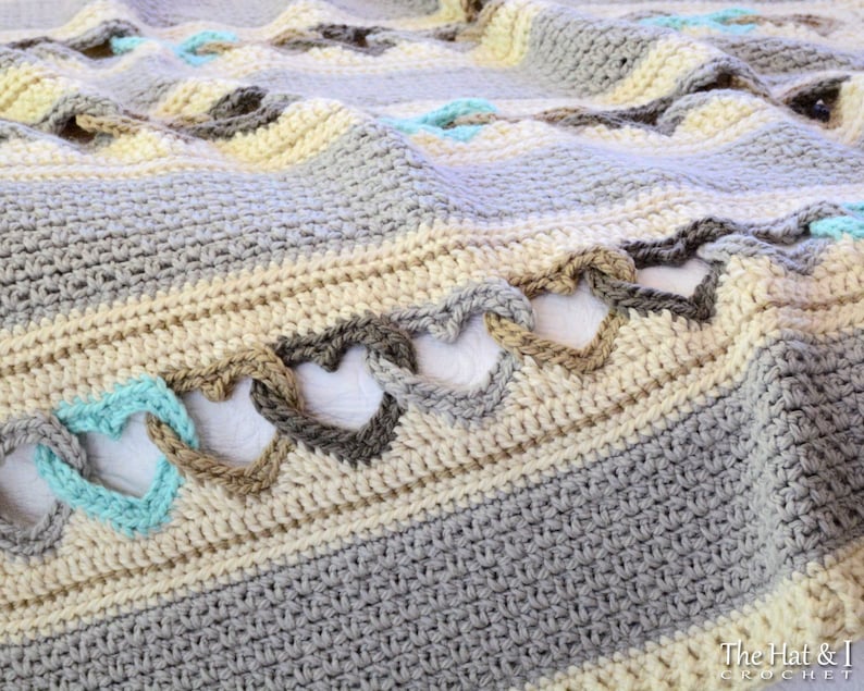 May include: A crocheted blanket with a heart pattern in shades of gray, beige, and teal.