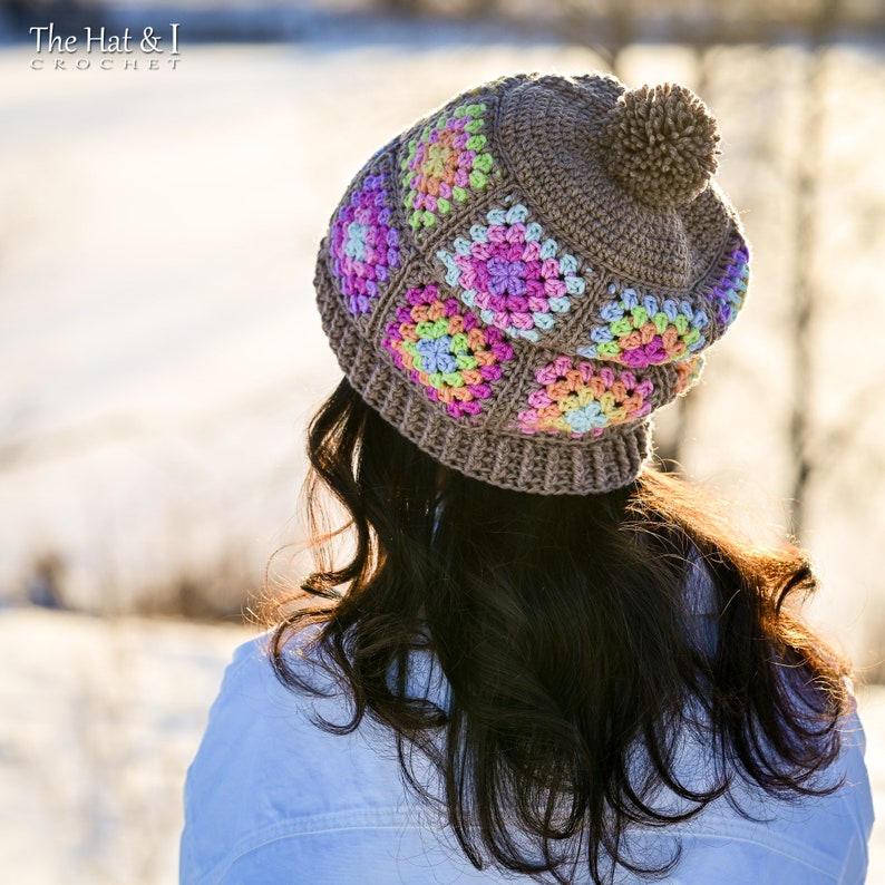 Puede incluir: Gorro de ganchillo marr&oacute;n con patrones cuadrados coloridos. El gorro tiene un pomp&oacute;n y el texto "The Hat & I Crochet". Los cuadrados coloridos incluyen tonos de rosa, amarillo, azul y verde. Accesorio de invierno.