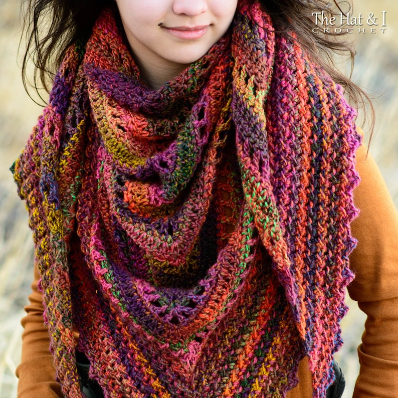 Puede incluir: Un chal de ganchillo colorido con un patr&oacute;n de encaje. El chal est&aacute; hecho con una variedad de colores, incluyendo rojo, naranja, amarillo, verde, azul y morado. El chal est&aacute; drapeado sobre los hombros de una persona que lleva una camisa marr&oacute;n.