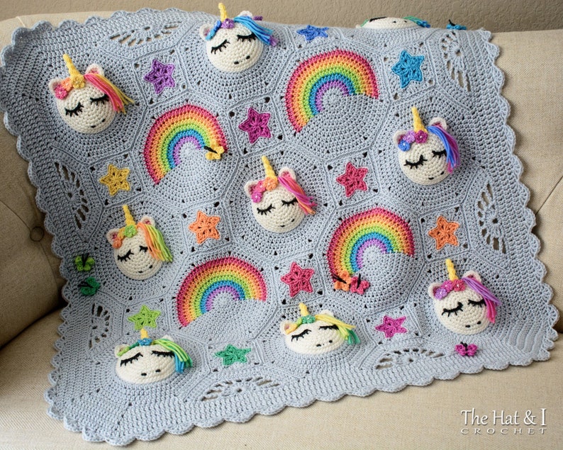 Puede incluir: Una manta de beb&eacute; de crochet gris con un tema de arco&iacute;ris y unicornio. La manta presenta m&uacute;ltiples aplicaciones de arco&iacute;ris y unicornio. La manta tiene un borde festoneado.