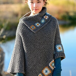 May include: A gray crocheted poncho with a cowl neck and decorative floral squares in blue, orange, and white. The poncho has a textured stitch pattern and is worn by a person. The text "The Hat & I Crochet" is in the upper right corner.