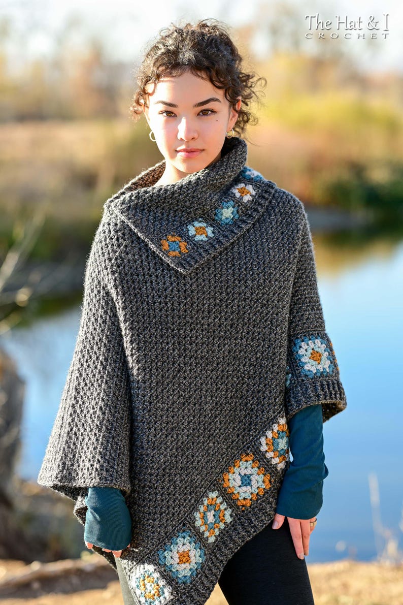 May include: A gray crocheted poncho with a cowl neck and decorative floral squares in blue, orange, and white. The poncho has a textured stitch pattern and is worn by a person. The text "The Hat & I Crochet" is in the upper right corner.