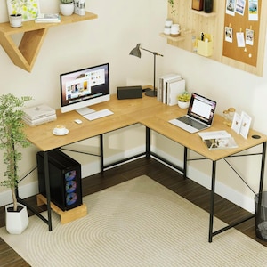 Pode incluir: Uma secretária de madeira em forma de L com pernas de metal preto, um monitor de computador e um laptop. A secretária está num ambiente de escritório em casa, com um tapete, uma planta e prateleiras decorativas. A torre do computador é preta com luzes coloridas.