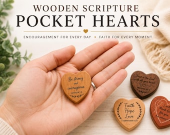 May include: Four small heart-shaped wooden tokens featuring engraved scripture verses. One token is held, while three others rest nearby. The text includes 'Be strong and courageous', 'Trust in the Lord', 'Faith Hope Love', and 'I will thank God for you'.