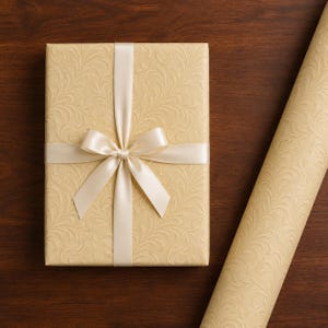 May include: A rectangular gift box wrapped in light beige paper with an embossed swirling leaf pattern, tied with a smooth cream-colored satin ribbon bow, accompanied by a matching roll of the same patterned wrapping paper.