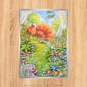 Könnte beinhalten: Eine lebendige Illustration eines schlafenden, orangefarbenen, fuchsähnlichen Wesens in einer üppigen, grünen Waldlandschaft. Das Kunstwerk zeigt einen gewundenen Pfad, bunte Blumen und einen hellblauen Himmel, mit dem Text "WANDERLINE ART STUDIO" unten.