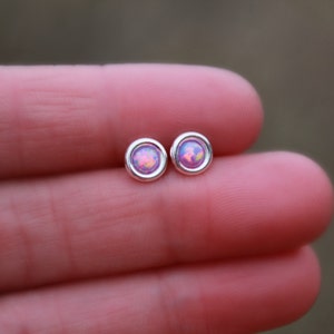 May include: A pair of silver stud earrings with pink opal stones.
