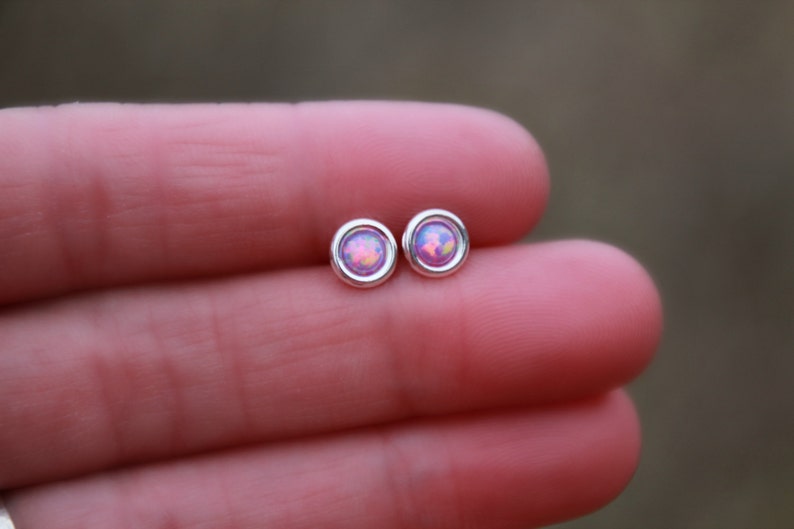 May include: A pair of silver stud earrings with pink opal stones.