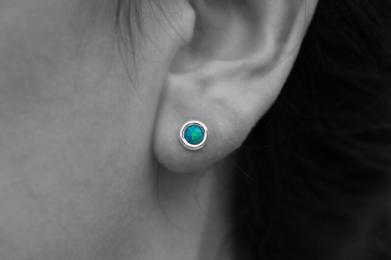 May include: A pair of silver stud earrings with a round blue opal gemstone in the center.