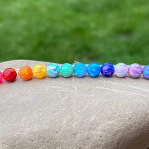 May include: A rainbow opal bead bracelet with a silver chain. The beads are iridescent and range in color from white to red.