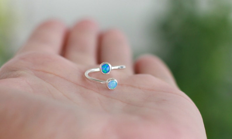 May include: A silver ring with two opal stones, one blue and one white.