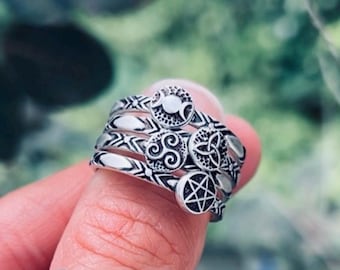 以下が含まれることがあります： 4 つのバンドが付いた銀のリングで、それぞれ異なるシンボルが描かれています。シンボルには、トリプルムーン、トリケトラ、ケルトの結び目、ペンタグラムが含まれています。