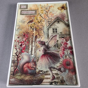 May include: A rectangular decorative tray with a whimsical autumn scene. It features a fairy, squirrel, and a small house, with the words "FALL ADVENTURES" at the top. The artwork is framed in a white border.