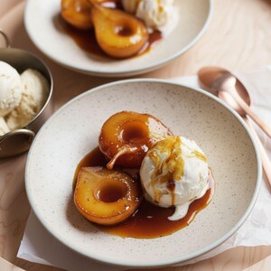 May include: A plate of poached pears with a scoop of vanilla ice cream, drizzled with caramel sauce. The pears are golden brown and sit in a pool of sauce. The ice cream is white and creamy.
