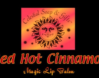 Op de afbeelding: Red Hot Cinnamon Magic Lip Balm van Celestial Soap & Gifts. Het etiket toont een gestileerde zon met een glimlachend gezicht.
