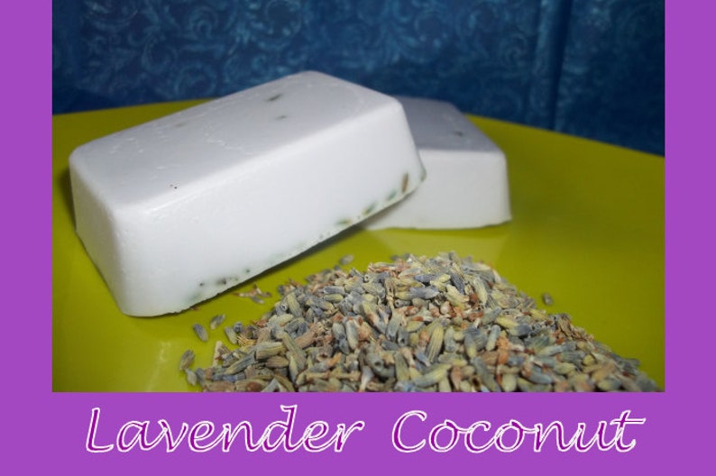 May include: Two bars of white soap with lavender buds embedded in the soap. The soap is on a yellow plate with dried lavender buds scattered around the soap.