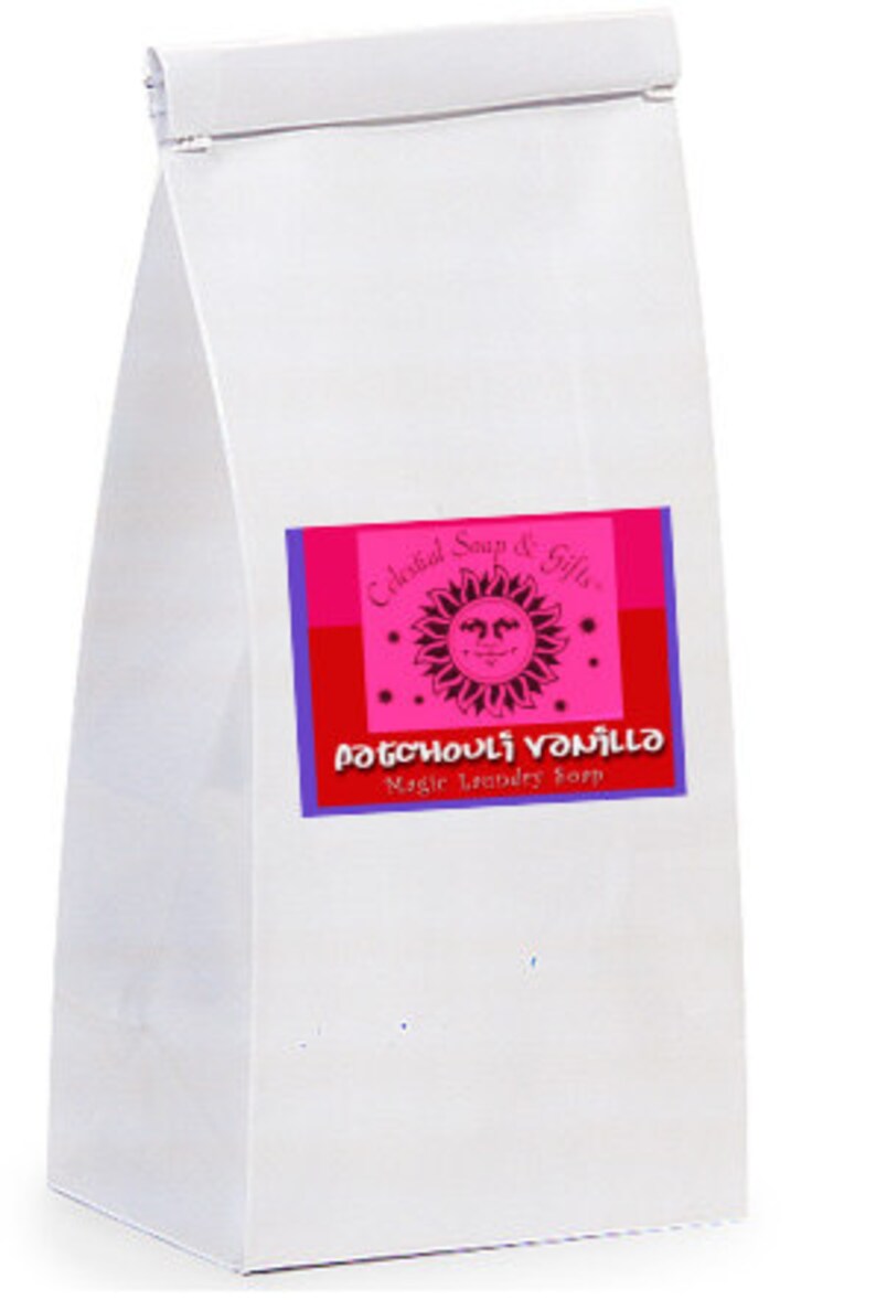 Op de afbeelding: Een witte papieren zak met een roze en blauw label waarop "Celestial Soap & Gifts" en "Patchouli Vanilla Magic Laundry Soap" staat.