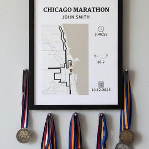 May include: A framed print with the text "CHICAGO MARATHON" and a map of the race route. Below the frame are several medals with colorful ribbons. The print includes the name "JOHN SMITH", time 3:48:55, and date 10.12.2025.