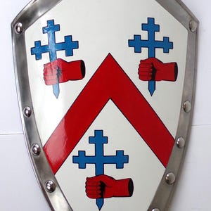 Może przedstawiać: Tarcza heraldyczna z białym tłem, czerwonym szewronem i niebieskimi krzyżami. Tarcza ma srebrną obwódkę z nitami. Projekt zawiera czerwone dłonie trzymające niebieskie miecze. Nazwa "Mc Crory" jest napisana na bannerze.