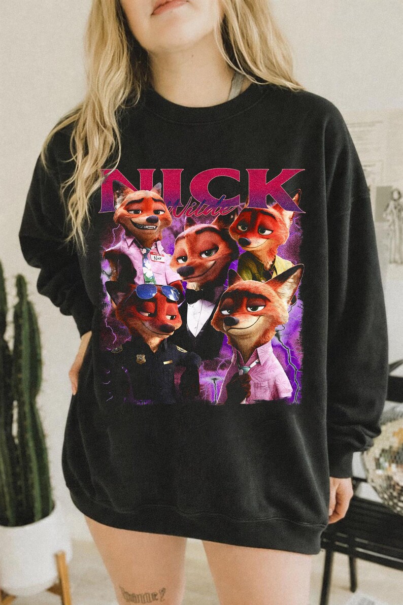 Op de afbeelding: Zwarte sweatshirt met een afbeelding van Nick Wilde uit Zootopia in verschillende outfits. Het woord "NICK" staat in roze en paars boven de afbeelding. Een casual, comfortabele stijl.