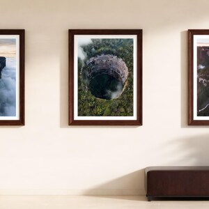 Può includere: Tre stampe artistiche da parete incorniciate con fotografie aeree di paesaggi. La stampa a sinistra mostra una montagna dalla cima piatta sopra le nuvole, quella centrale una dolina circolare in una foresta e quella a destra una cascata.