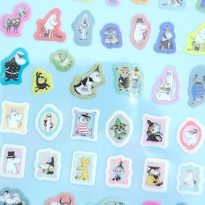 May include: A sheet of mini stickers featuring Moomin characters. The stickers are in various shapes and colors, with a light blue background. The packaging reads "MOOMIN MINI MINI DECO STICKERS".