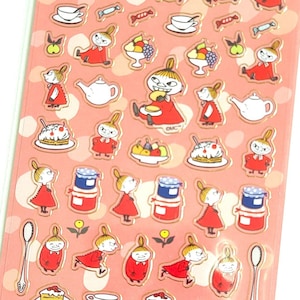 May include: Sheet of Moomin stickers featuring various characters and objects like teacups, cakes, and jars of jam. The stickers are on a pink background with a white polka dot pattern. The text "MOOMIN STICKERS" is at the top.