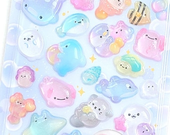 May include: A sheet of colorful, translucent stickers featuring various sea creatures and bubble shapes. The stickers have a glossy finish and are in shades of pink, blue, yellow, and orange. Text on the packaging reads "POP SEAL" and "UMINOIKIMONO".