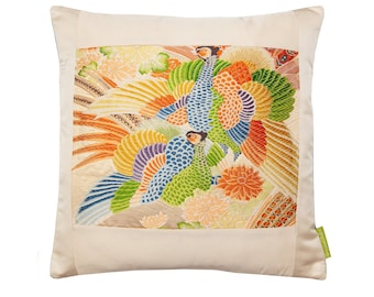 Könnte beinhalten: Ein weißes Kissen mit einem bunten gestickten Design aus Pfauen und Blumen. Das Design ist mit einem cremefarbenen Rand umrahmt.