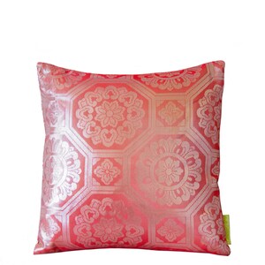 May include: A red pillow with a gold floral pattern. The pillow is made of a soft, luxurious fabric and has a subtle sheen.