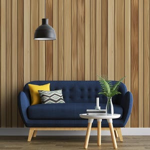 May include: A modern living room scene featuring a navy blue sofa with yellow and patterned pillows. A small white table with a fern and candle sits in front of the sofa. The background is a vertical wood panel wall, and a black pendant light hangs above.