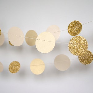 May include: A garland of beige and gold circles, some with glitter, strung together with white thread.