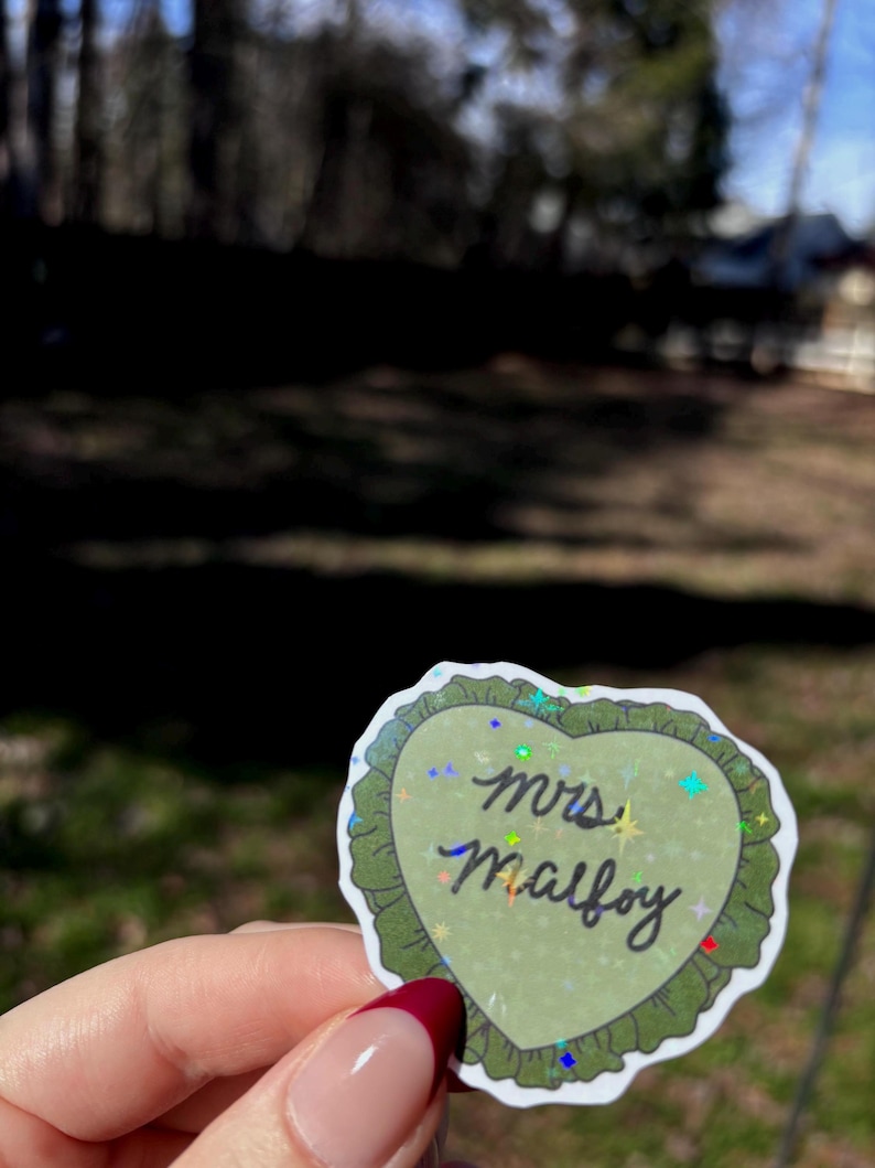 Channel your Slytherin romance era with this “Mrs. Malfoy” inspired sticker, perfect for fans of Draco Malfoy and the world of Harry Potter 🐍✨
This heart-shaped sticker features a soft green design with holographic sparkle details and is laminated for durability, making it perfect for water bottles, Kindle cases, laptops, journals, and planners. A must-have for bookish girlies and wizarding romance lovers.
✨ Fan-made, inspired design.