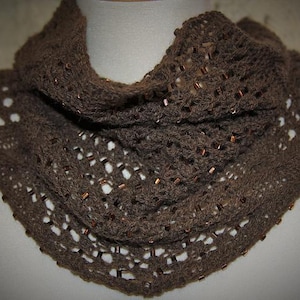 May include: A brown, open-weave scarf with a cowl neck design. The scarf is adorned with small, copper-colored beads throughout the knitted fabric. The scarf is displayed on a white mannequin.