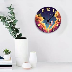 May include: Round wall clock with a space theme. The clock face features a rocket ship blasting off through clouds, with a starry night sky background. The numbers are in a gold color.