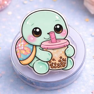 May include: A cute, cartoon-style turtle sticker in shades of green, pink, and brown. The turtle is holding a bubble tea drink with a pink lid and straw. The turtle has a floral design on its shell and is set on a clear, round base.