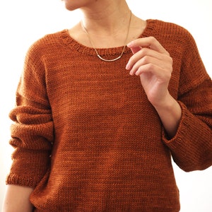 May include: A brown knitted sweater with long sleeves and a round neckline.